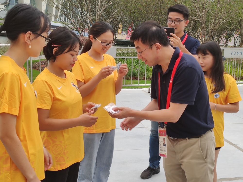 施欣副校长向志愿者赠送校庆徽章及海贝贝钥匙扣